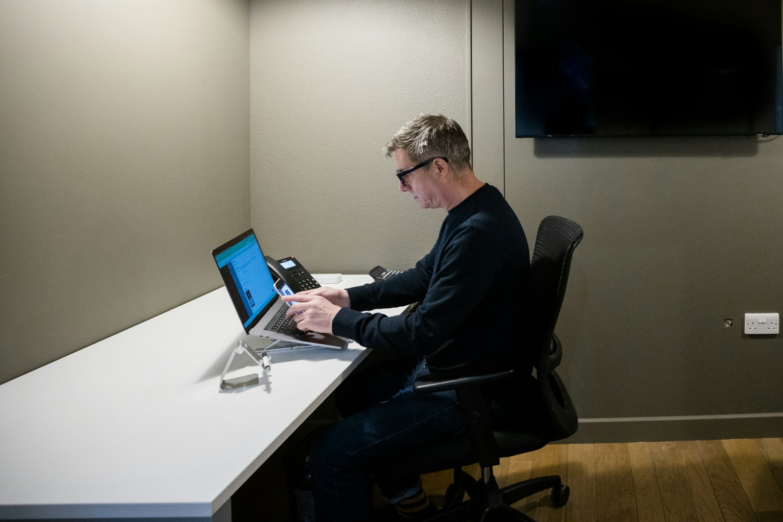 Office worker entering information on a laptop at a desk in London